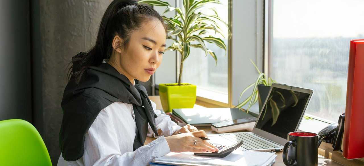 Accountant working with a calculator and laptop in a bright office